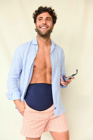 SIIL pánský stomický pás v námořnické modré Usmívající se muž v rozepnuté světle modré košili, s tmavě modrým stomickým pásem a pruhovanými šortkami